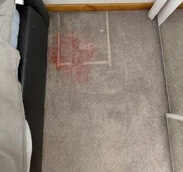 Before: light grey bedroom carpet with a red stain beside the bed