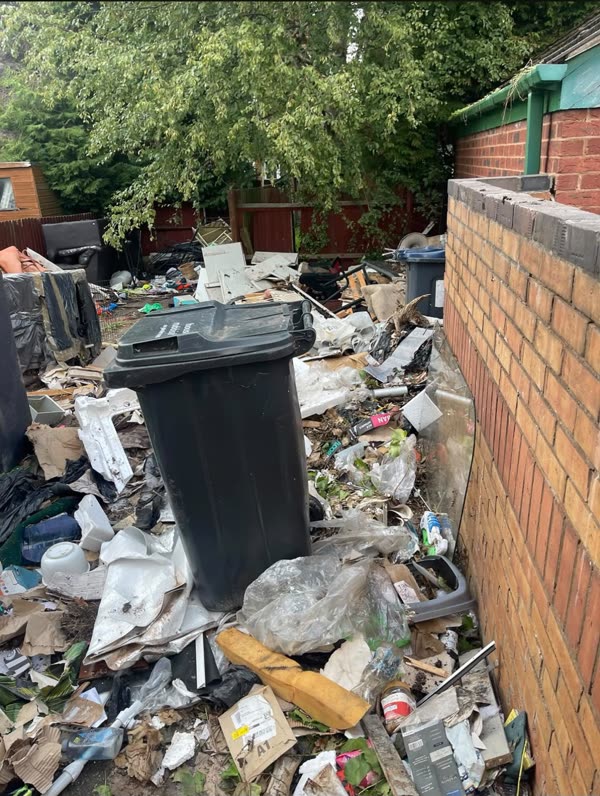 Before: back yard piled high with rubbish bags, broken furniture and loose waste